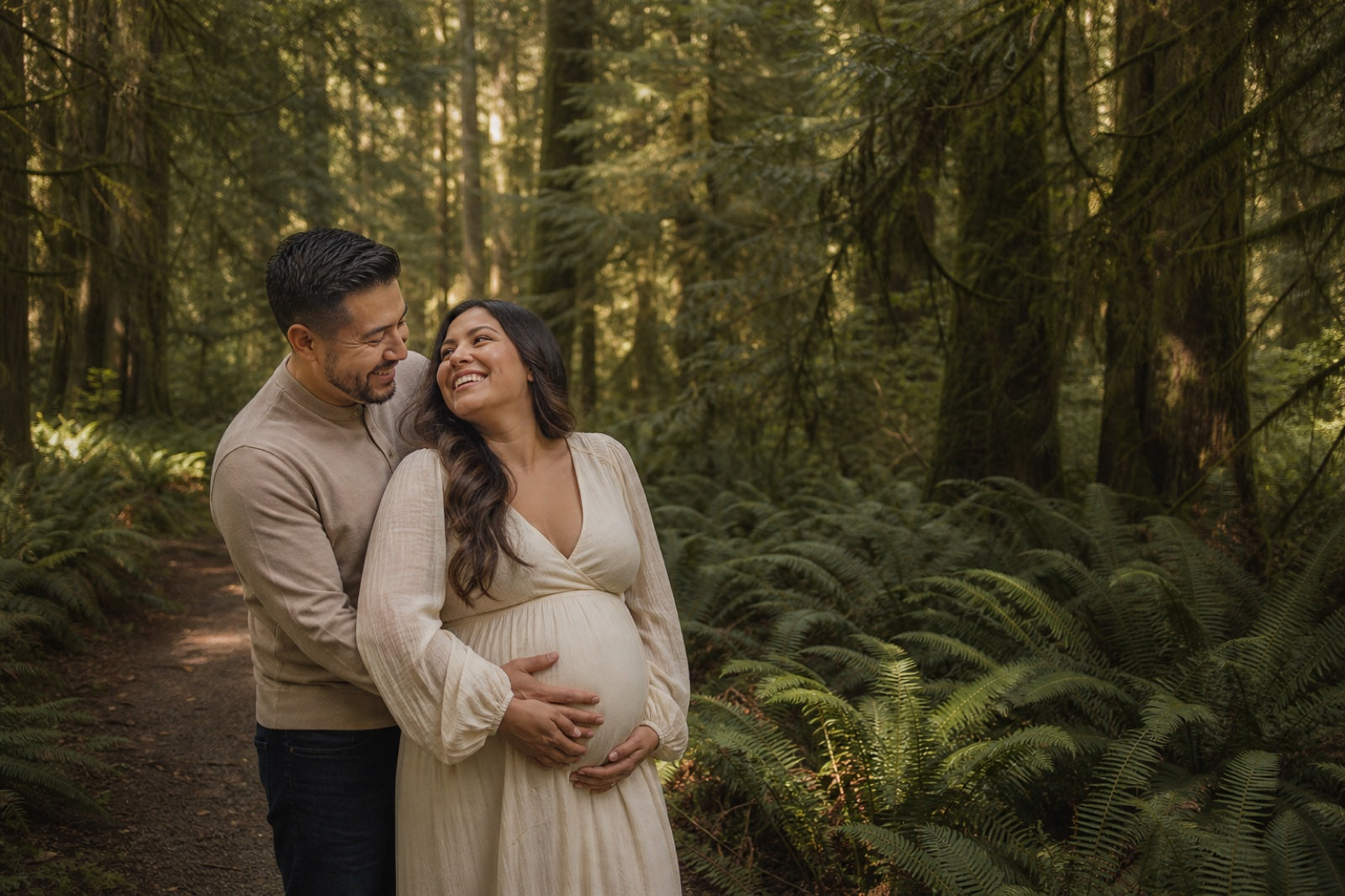 Expectant couple standing together in a Pacific Northwest forest
